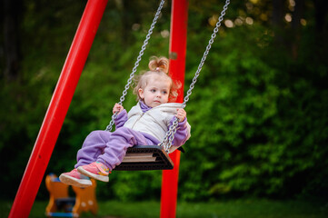 A little one experiences the joy of swinging, her tentative hold and soft focus gaze evoking the...