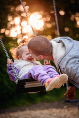 Heartwarming laughter fills the air as a toddler gleefully swings towards her parent, encapsulating...