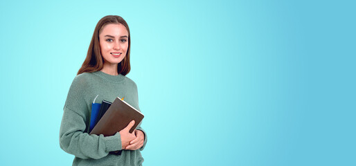 A smiling woman holding books against a teal background, represe