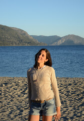 portrait of Latin American brunette woman, with lake and mountains background on vacation enjoying the place