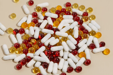 A pile of white, yellow and red pills on a beige background. The concept of pharmacy, dietary supplements, health care. background for your design