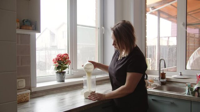 woman tidying up the kitchen and pouring flour into a container organizing space
