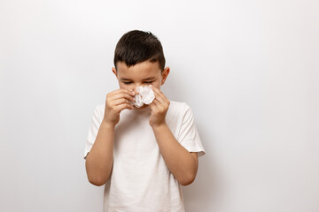 A guy on a white background blows his nose into a handkerchief.