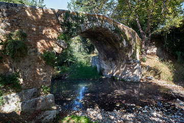 A stone, historic bridge over a mountain stream on the island of Crete