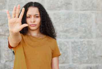 Stop, hand and portrait of woman for warning, rejection or sign against wall. Serious, gesture and face of gen z female person for sexual harassment, discrimination or gender equality in outdoor