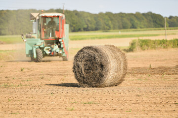 A tractor cleans the field with flax and makes bales