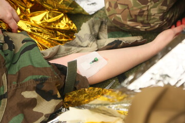 A medical instructor inserted a catheter into the arm of a wounded soldier.