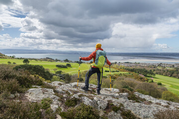 Hiking in Ireland, traveler with his backpack admiring the landscape of Dublin Bay