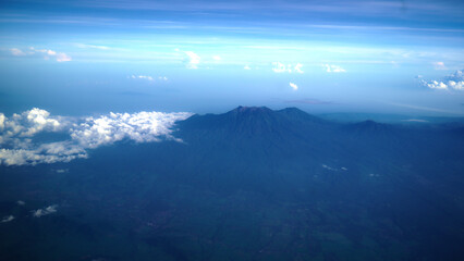 Obraz premium Aerial view of Bali island from the airplane window. The earth panorama with Bali island view , mountain, blue sky and white cloud background. Natural nature landscape background.