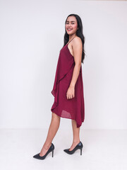 Elegant young Asian woman in maroon dress and black heels, isolated on white