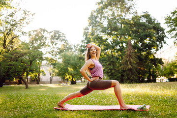 Young woman in the park on a green lawn doing exercises, doing fitness, yoga. Fitness. Active...
