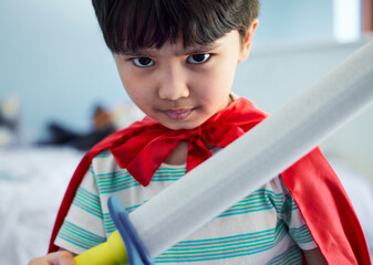 Boy, cape and sword with playing in portrait for child development with superhero, confidence and...