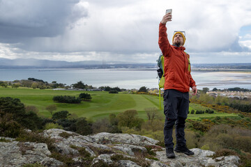 Searching for signal, connection, hiker on mountain top trying to communicate with mobile phone.