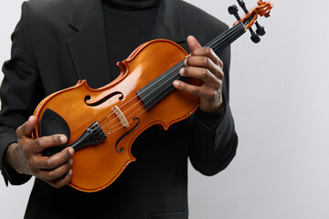 Professional musician in suit presenting elegant violin on white background for classical music...