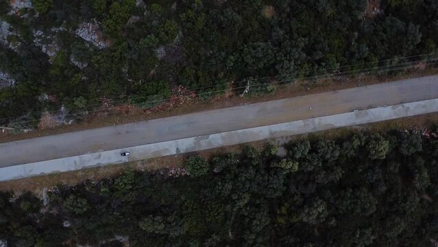 Motorcyclist rides on forest road. Drone footage.