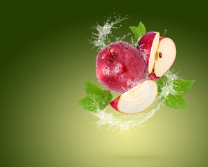 Water splash on fresh red apple with leaves isolated on green background