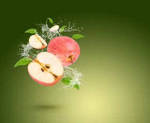 Water splash on fresh apple with leaves isolated on green background