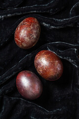 Eggs stained with wine and covered with mother-of-pearl on a dark velvet background. Easter concept. - 790176896