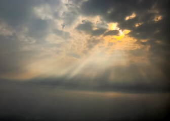 Background with copy space of sun rays through broken clouds over the ocean