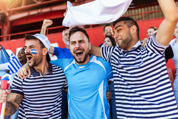 Greece fans cheering at the game on stadium. Wearing blue and white colors to support their team. Celebrating with flags and scarfs. - 790182259