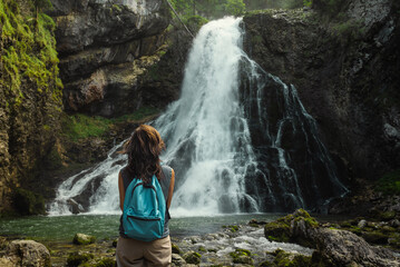 A woman standing at the Gollinger Waterfall in Torren, a district of Golling. - obrazy, fototapety, plakaty