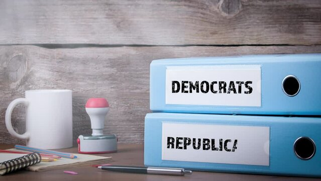 DEMOCRATS REPUBLICANS. Binders on wooden desk in the office. Business background