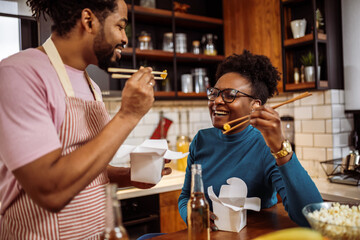 African American couple eating sushi together at home. - 790197053