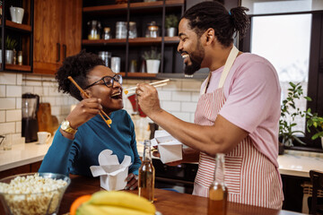 African American couple eating sushi together at home.