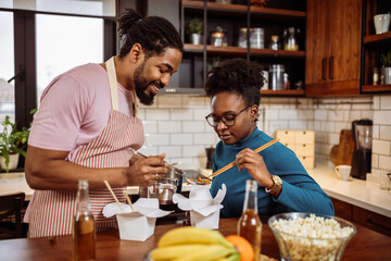 African American couple eating sushi together at home. - 790197221