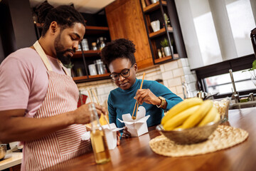 African American couple eating sushi together at home.