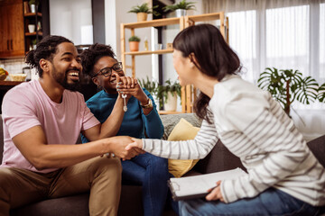 Multiracial couple buying a flat, house from Asian real estate agent. Shaking hands to make a deal. - 790197427