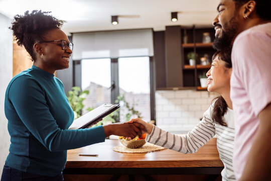 African American boyfriend and Asian girlfriend shaking hands with their real estate agent. Making deals for their new home.