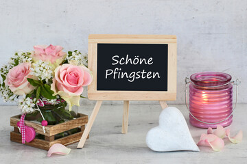 Rosenstrauß mit Herz und dem Text schöne Pfingsten auf einer Kreidetafel.