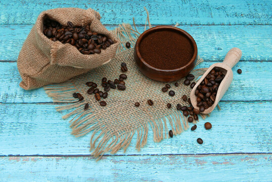 Arrangement mit einem Sack Kaffeebohnen und gemahlenem Kaffee auf t&uuml;rkisfarbenem Holzhintergrund.