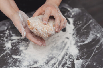 Unrecognizable woman hands with freshly baked delicious homemade ciabatta bread in hands in kitchen