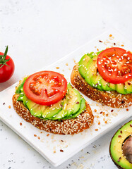 avocado, tomato and sesame seeds sandwiches; tasty breakfast; close up and copy space