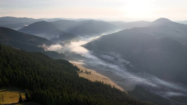 Aerial footage on the top of the Carpathian Mountains in Romania. Early morning with fog in the valley in the Carpathian Mountains in Romania. Tibau valley in Carpathian, Carlibaba, Suceava, Romania.