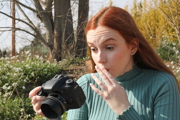 Photographer with his hand on his face looks with great amazement at the image he has made with his...