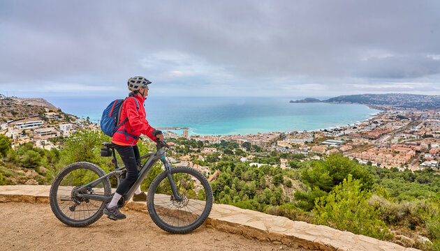 activ senior woman riding her electric mountain bike in the city of Xabia, Costa Blanca, Spain, Europe