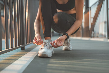 Close up - Running shoes runner woman tying laces sneakers for summer run in the city. Jogging girl exercise motivation health and fitness exercise, lifestyle.