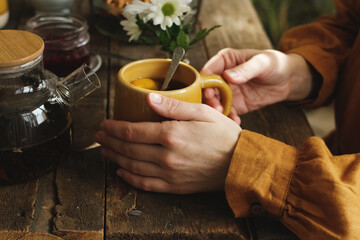 Rustic morning breakfast. Person drinking tea with lemon slice.
