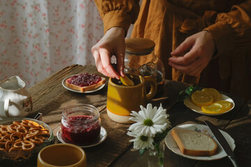 Tea time. Morning breakfast. Woman adds lemon slice into cup of tea.