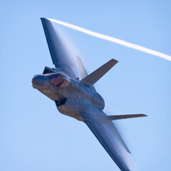 Close view of a F-35C Lightning II  approaching in a high G maneuver, with condensation clouds over...