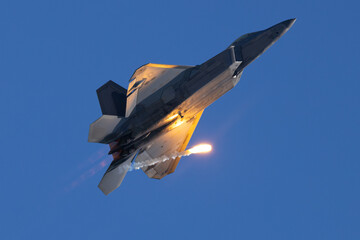 Bottom view of a F-22 Raptor deploying a flare in beautiful light