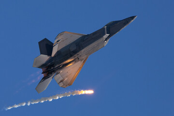 Bottom view of a F-22 Raptor deploying a flare in beautiful light