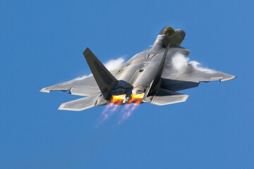 F-22 Raptor in a high G maneuver, with afterburners on and condensation clouds around the cockpit