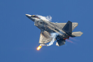 F-22 Raptor in a high G maneuver deploying flares, with afterburners on and condensation clouds...