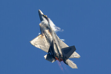 F-22 Raptor in a high G maneuver, with afterburners on and condensation clouds around the cockpit