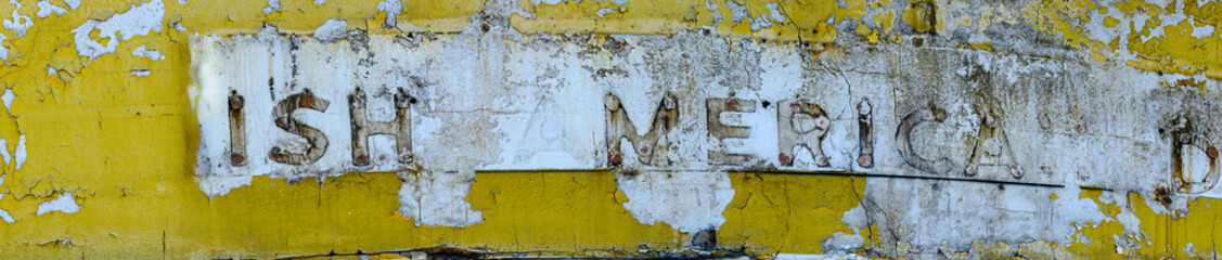 Close-up panorama section of a vintage gas station sign with missing letters and peeling paint.