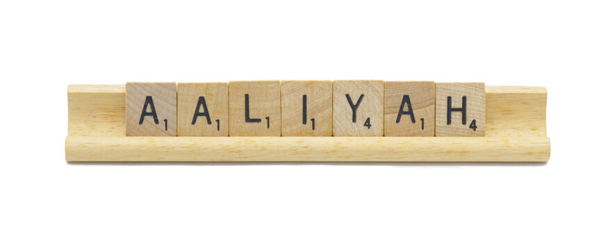 Miami, FL 4-18-24 popular baby girl first name of AALIYAH made with square wooden tile English alphabet letters with natural color and grain on a wood rack holder isolated on white background